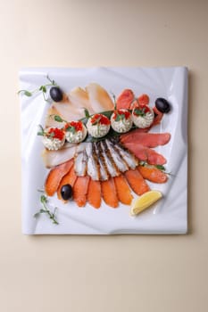 An artfully arranged platter of fresh seafood - salmon, trout, caviar, and shrimp - on a white plate with lemon slices and greens. A visually appealing still life composition.