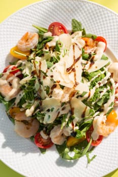 Delicious and healthy salad with greens, cherry tomatoes, and grilled shrimps. Served on a white plate, the image features a clean, modern look. Perfect for stock agencies or as a mockup.