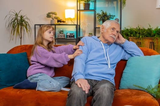 Compassion. Loving worried kind girl granddaughter consoling sad grandfather helping with problem comforting talking to upset senior man, empathy, support embracing sitting on sofa in living room.