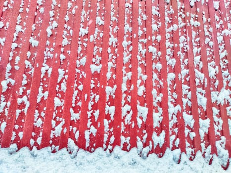 Fence made of galvanized corrugated board in the snow In the village after a snowfall. Abstract background, pattern, texture, place for text and copy space