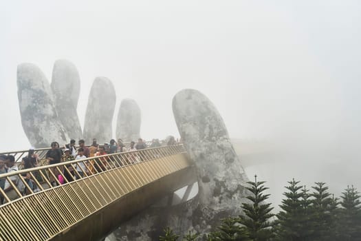 Danang, Vietnam - June 27, 2023: The Golden Bridge is lifted by two giant hands in the tourist resort on Ba Na Hill in Danang, Vietnam.