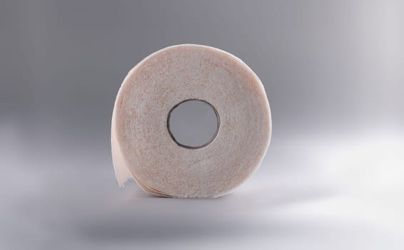Roll of toilet paper lying on gray background closeup. Prevention of hemorrhoids concept