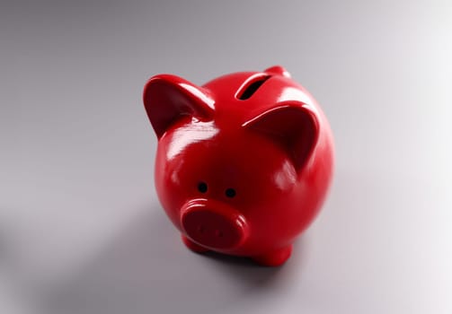 Red piggy bank standing on gray background closeup. Economic crisis concept