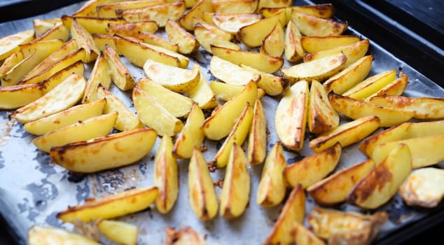 Baked potatoes lying on cooking paper on baking sheet closeup background. Homemade recipes concept