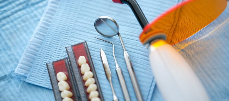 Dental instruments and dentures lying on sterile medical napkin in clinic closeup. Modern dental equipment concept