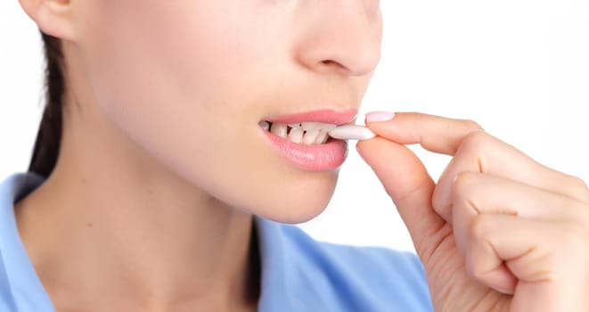 Woman putting chewing gum in her mouth with hand closeup. Protecting against caries after eating concept