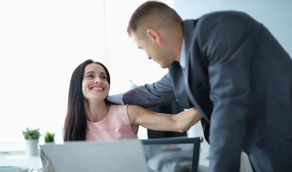 Young man and woman in business suits hugging at work in office. Love affairs at work concept