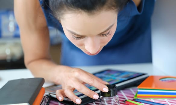 Woman designer looking through magnifying glass at color samples on paper palette. Designer assistance in choosing color matching concept