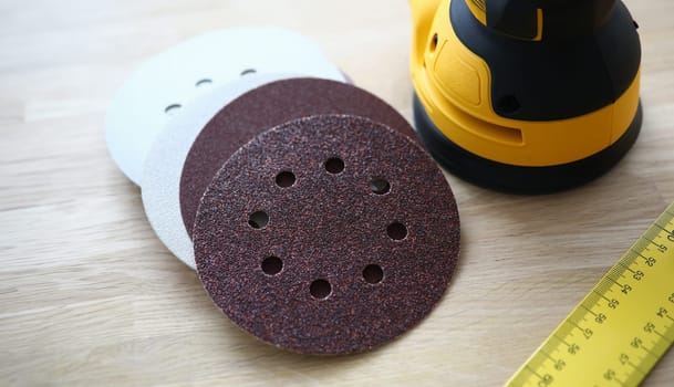 Close-up of sander machine with replacement discs on table. Grinding equipment for renovation and construction site. Professional device for work with wood texture