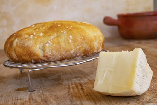 wedge of artisanal caciotta cheese near a loaf of homemade bread