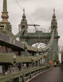 London, UK -​ Dec 25, 2023 - Traditional metal Hammersmith bridge for pedestrians and cyclists over the River thames. One of the world's oldest suspension bridges and a major river crossing and primary route in west london, Cast-iron bridge, Space for text, Selective focus.