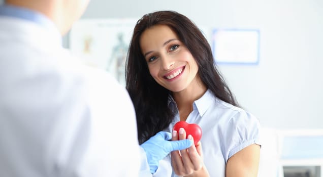 Portrait of cheerful woman looking at camera with gladness. Smiling female person at consultation with experienced cardiologist in clinic. Health care and cardiology concept