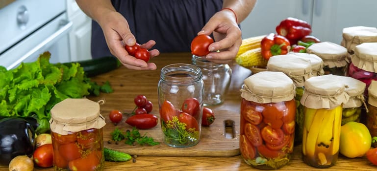 Woman canning vegetables in jars in the kitchen. Selective focus. Food.