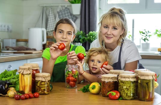 Family canning vegetables in jars in the kitchen. Selective focus. Food.