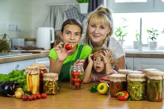 Family canning vegetables in jars in the kitchen. Selective focus. Food.