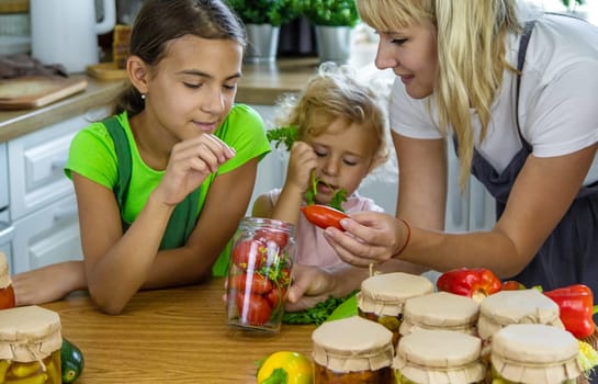 Family canning vegetables in jars in the kitchen. Selective focus. Food.