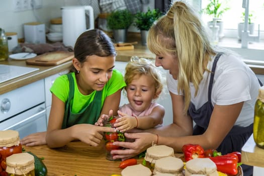 Family canning vegetables in jars in the kitchen. Selective focus. Food.