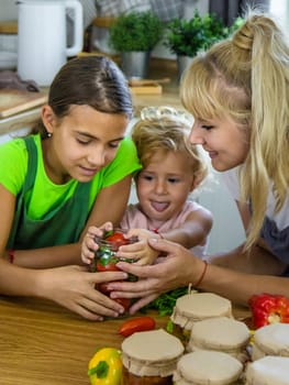 Family canning vegetables in jars in the kitchen. Selective focus. Food.