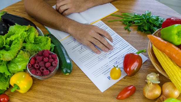 A nutritionist writes a nutrition plan. Selective focus. Food.