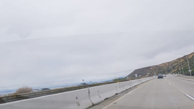 Driving along Highway 101 near Rincon Beach, California, amidst a gloomy, cloudy winter day.