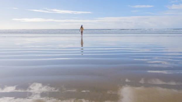 Little girl, braving the cold, joyfully runs in her swimsuit across the beach during winter.