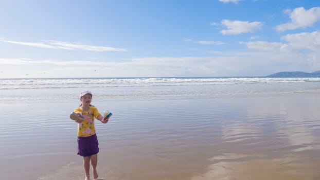 Little girl, braving the cold, joyfully runs in her swimsuit across the beach during winter.