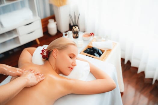 Caucasian woman customer enjoying relaxing anti-stress spa massage and pampering with beauty skin recreation leisure in day light ambient salon spa at luxury resort or hotel. Quiescent