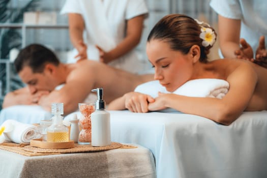 Caucasian couple customer enjoying relaxing anti-stress spa massage and pampering with beauty skin recreation leisure in day light ambient salon spa at luxury resort or hotel. Quiescent