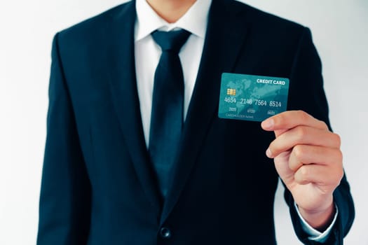 Portrait of businessman holding a credit card showing front view to the camera in close up view. Online shopping business and cashless payment concept. uds