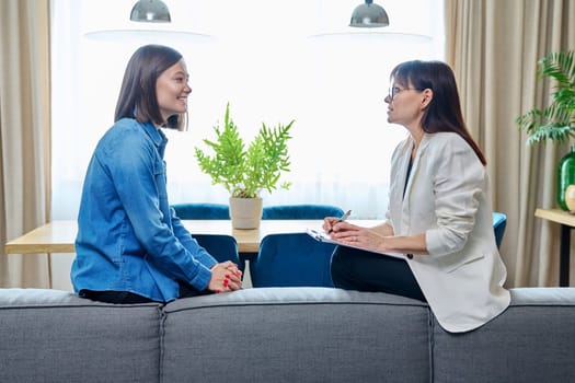 Happy joyful young woman patient talking to female psychologist counselor at therapy session. Positive treatment results, mental health of youth. Psychology psychotherapy support help rehabilitation