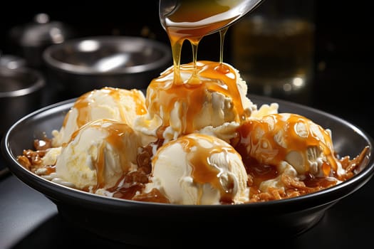 Vanilla ice cream scoops in a black bowl topped with caramel, large serving of ice cream close-up.