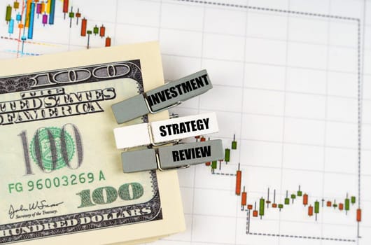 Business concept. On the quote chart there are dollars and clothespins with the inscription - Investment Strategy Review