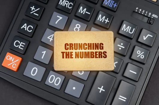 Financial concept. There is a sign on the calculator that says - Crunching the numbers