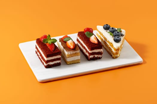 Strawberry and blueberry cakes on an orange background.