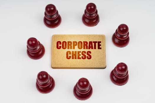 Business concept. On a white background, pawns stand around a sign with the inscription - Corporate Chess