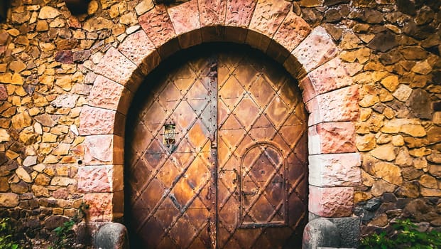 A wooden door is a fixture in the middle of a stone wall, adding a touch of art to the brickwork facade of the building