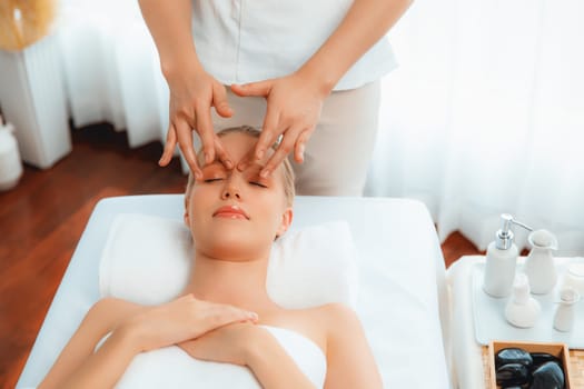 Caucasian woman enjoying relaxing anti-stress head massage and pampering facial beauty skin recreation leisure in dayspa modern light ambient at luxury resort or hotel spa salon. Quiescent