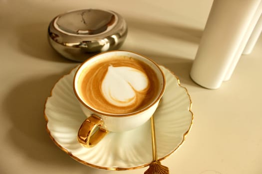 A cup of coffee with a heart symbol on a golden saucer. High quality photo