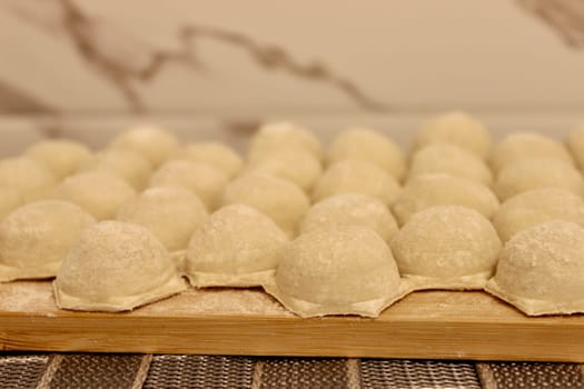 Dumplings made of dough and minced meat are stuck on the board. High quality photo