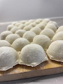 Dumplings made of dough and minced meat are stuck on the board. High quality photo