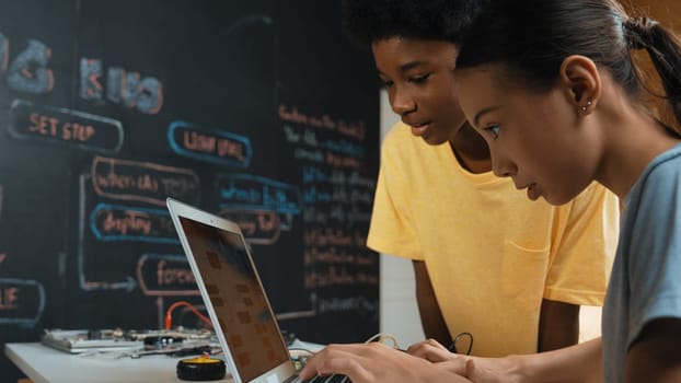 Group of diverse student working together to write program. Multicultural children coding or programing program while teacher holding laptop and looking at smart learner at STEM class. Edification.