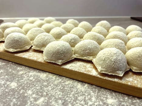 Dumplings made of dough and minced meat are stuck on the board. High quality photo