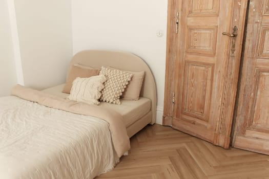 Cozy bed with pillows and blanket in room with old wooden door and floor. High quality photo