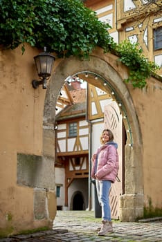 Winter Fun in Bitigheim-Bissingen: Beautiful Girl in Pink Jacket Amidst Half-Timbered Charm. Step into the festive winter spirit with this captivating image of a lovely girl in a pink winter jacket standing in the archway of the historic town of Bitigheim-Bissingen, Baden-Württemberg, Germany. The backdrop features charming half-timbered houses, enhanced by warm vintage photo processing, creating a delightful scene of winter joy and architectural beauty.