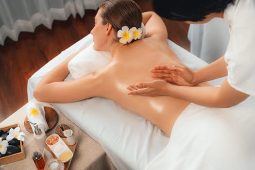 Caucasian woman customer enjoying relaxing anti-stress spa massage and pampering with beauty skin recreation leisure in day light ambient salon spa at luxury resort or hotel. Quiescent