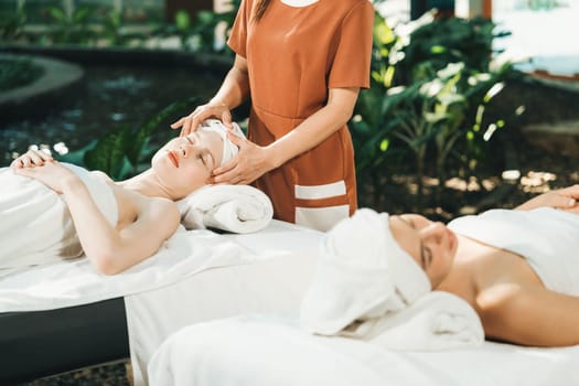 A portrait of two caucasian woman with beautiful skin having facial massage while falling the deep state of relaxation surrounded by outdoor natural and peaceful environment. Tranquility.