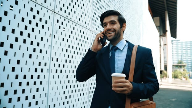 Smart business man using phone to talking about business investment. Happy manager walking at street while talking on smart phone to discuss business plan or marketing strategy or working. Exultant.