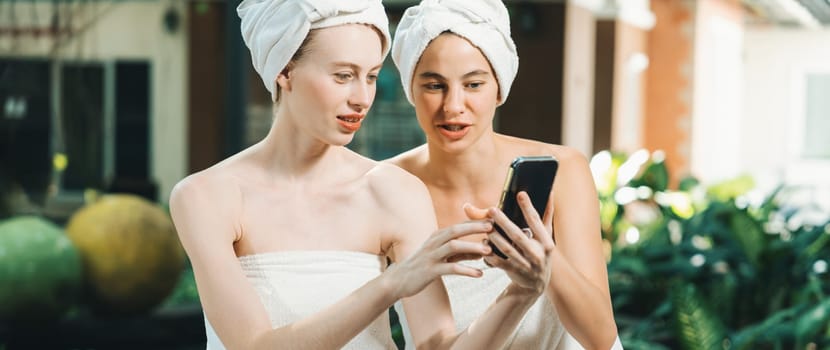 Couple of young beautiful women with beautiful skin in white towel taking a photo together at outdoor surrounded by peaceful natural environment. Beauty and healthy spa concept. Tranquility.