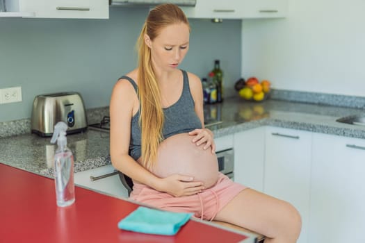 A tired pregnant woman sits in the kitchen after cleaning. Health and vitality of a pregnant woman.