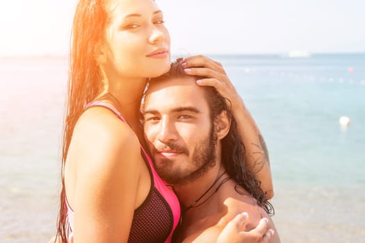 Close up shot of beautiful young caucasian woman with black hair and freckles looking at camera and smiling. Cute woman portrait in a pink bikini posing on a volcanic rock high above the sea